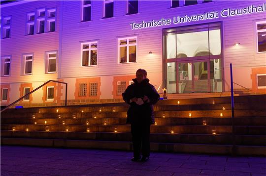 Iris Künstel steht vor dem in den Farben blau und gelb der Ukraine leuchtenden Hauptgebäude der Uni und hat gerade wie viele weitere Besucherinnen des Weltgebetstags der Frauen eine Kerze auf die Treppe gestellt. Fotos: Hörseljau