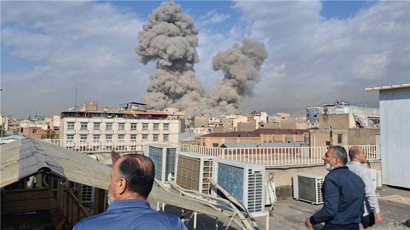 Israel greift den Iran an - Menschen beobachten Rauch nach einer Explosion in Teheran.