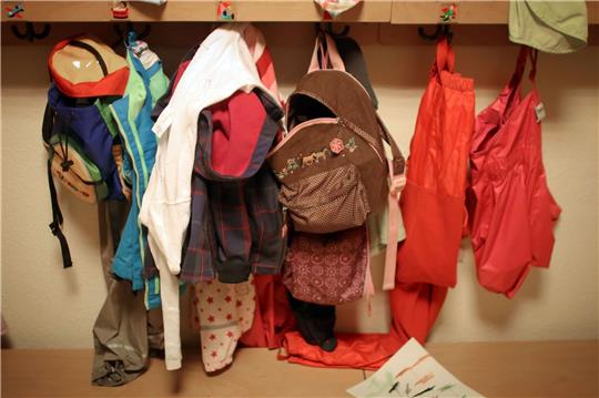 Jacken und Rucksäcke von Kindern in der Garderobe einer Betriebskita.