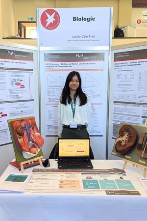 Jamila Cate Tran an ihrem Stand, mit Infografiken und Modellen von Organen.