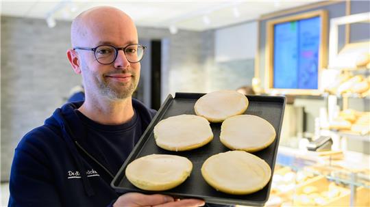 Jannik Harms, Geschäftsführer der De Heidbäcker GmbH, hält ein Blech „Grönländer“ in der Hand.