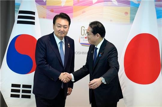 Japans Ministerpräsident Fumio Kishida und der südkoreanische Präsident Yoon Suk Yeol schütteln sich die Hände während ihres bilateralen Treffens anlässlich des G7-Gipfels.