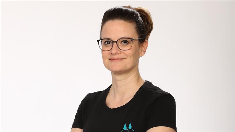 Das Foto zeigt Jasmin Frommhold lächelnd mit Brille und dunklem T-Shirt.