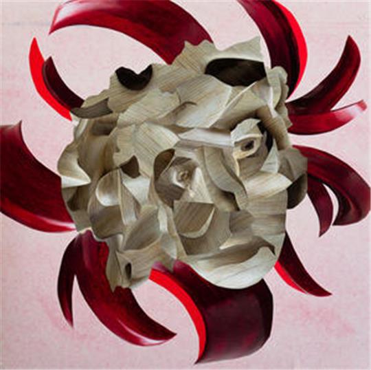 Skulptur eines menschlichen Gesichts aus hellbraunem Holz mit roten, geschwungenen Elementen im Hintergrund.