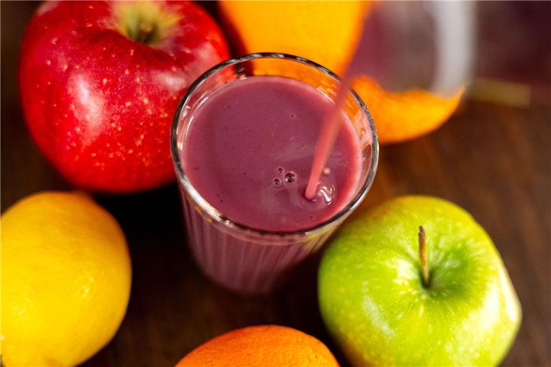 Jemand gießt roten Smoothie in ein Glas.