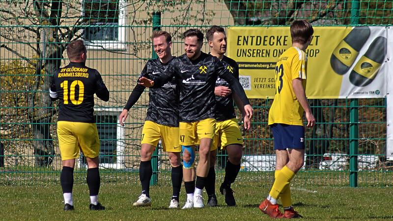 Fußballspieler in gelber und schwarzer Sportkleidung auf einem Spielfeld vor einem Tor, einige Spieler umarmen sich