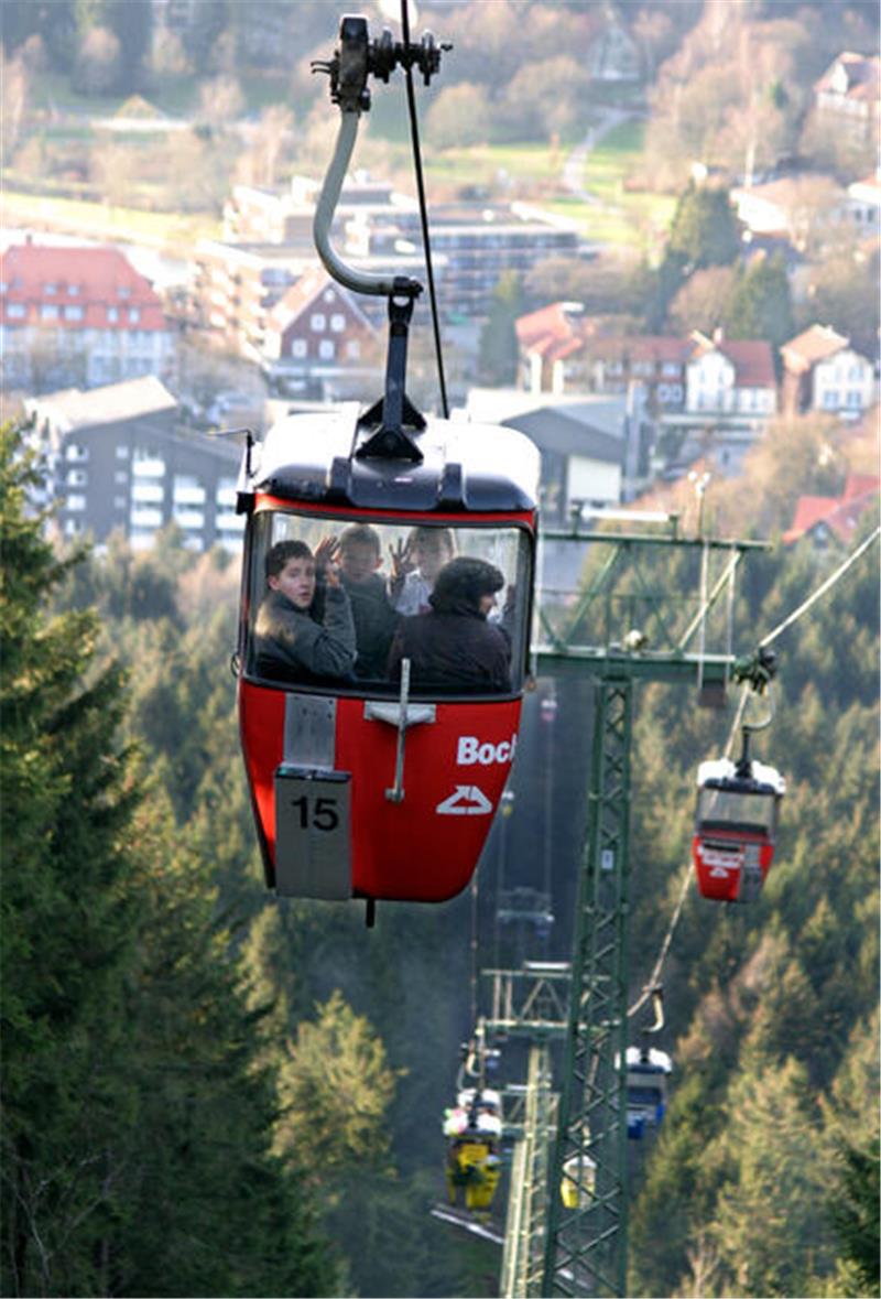 Hahnenklee rettet sich 2006 aus eigener Kraft und mit Goslarer Hilfe Rote Gondel der Seilbahn mit zwei Personen vor bewaldeter Landschaft und weiteren Gondeln in der Ferne