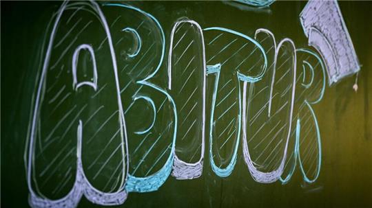 Eine Schultafel auf der mit Kreide „Abitur“ geschrieben steht.