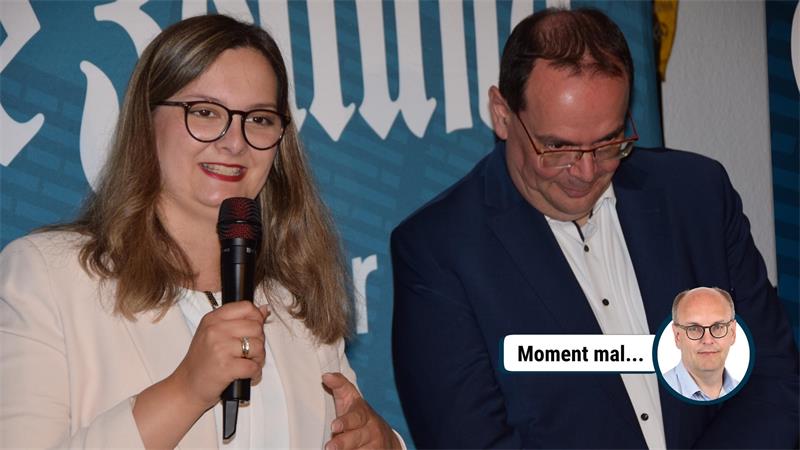 Frau mit Brille und Mikrofon spricht, Mann neben ihr schaut nach unten und lächelt