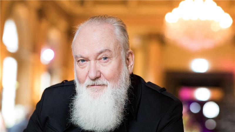 Joachim Witt: „Am besten bin ich, wenn es mir nicht so gut geht“ Joachim Witt mit langem, weißen Bart sitzt in einem Lokal.