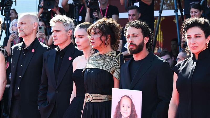 Joaquin Phoenix und Rooney Mara mit einem Teil des Filmteams und einem Foto von Hind Rajab auf dem roten Teppich. 