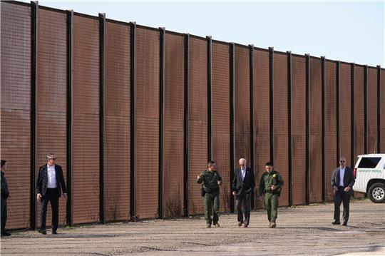 Joe Biden (M), Präsident der USA, besucht die Grenze zwischen den USA und Mexiko und geht mit US-Grenzschutzbeamten entlang eines Abschnitts am Grenzzaun in El Paso, Texas.