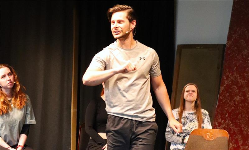 Ein junger Mann gestikuliert auf der Bühne.