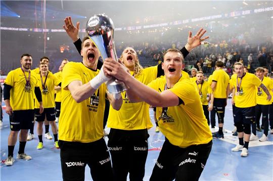 Joel Birlehm, Mikael Appelgren und David Späth von den Rhein-Neckar Löwen feiern mit dem Pokal.
