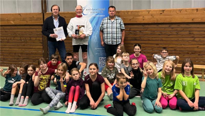 Jubilar im Hintergrund: Jürgen Blume (hinten Mitte) wird vom Kreissportbund-Vorsitzenden Volker Bäcker (l.) und Sportabzeichenreferent Markus Freitag für 60 Jahre Einsatz als Sportabzeichen-Prüfer ausgezeichnet. Der Nachwuchs der TSG Jerstedt freut sich mit Blume. Foto: Privat