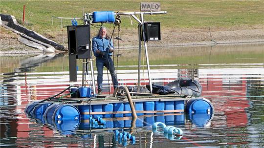 Jürgen Schwarzer bedient das Floß und steuert die Pumpe auf dem Grund des Schladener Badeteichs.
