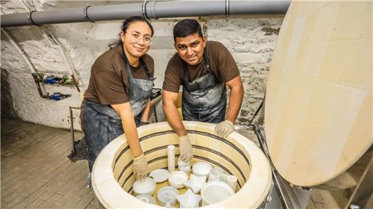 Julieth Andrea Bohorquez Ambrocio und Venkata Subramanian stehen an ihrem Brennofen, der mit Keramik gefüllt ist.