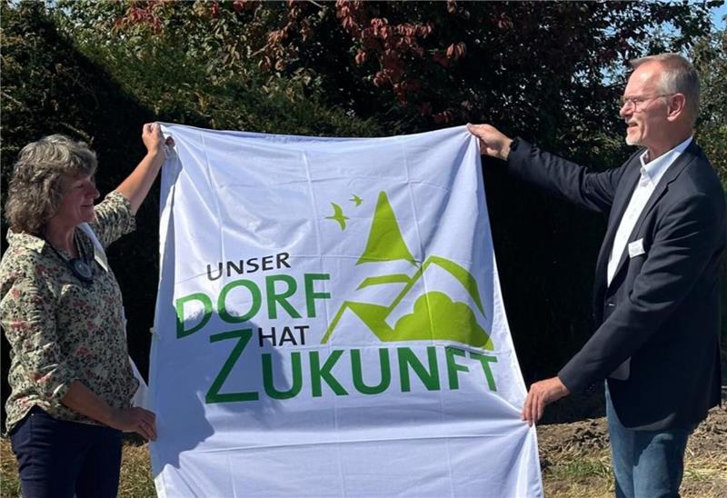 Unser Dorf hat Zukunft: Gielde scheitert knapp an der Bundesrunde Jury-Mitglied Ralf Gebken (Ministerium Ernährung, Landwirtschaft und Verbraucherschutz) überreicht ein Geschenk an Ortsbürgermeisterin Friederike Fiebig. Die Flagge soll einen guten Platz im Ort bekommen.