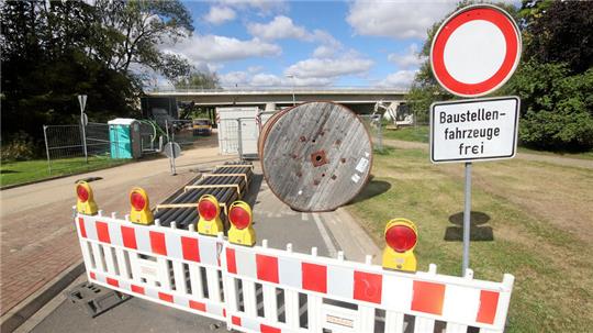 Kabeltrommeln und Rohre lagern im Baustellenbereich, um die unter der maroden Brücke verlaufenden Versorgungsleitungen verlegen zu können.