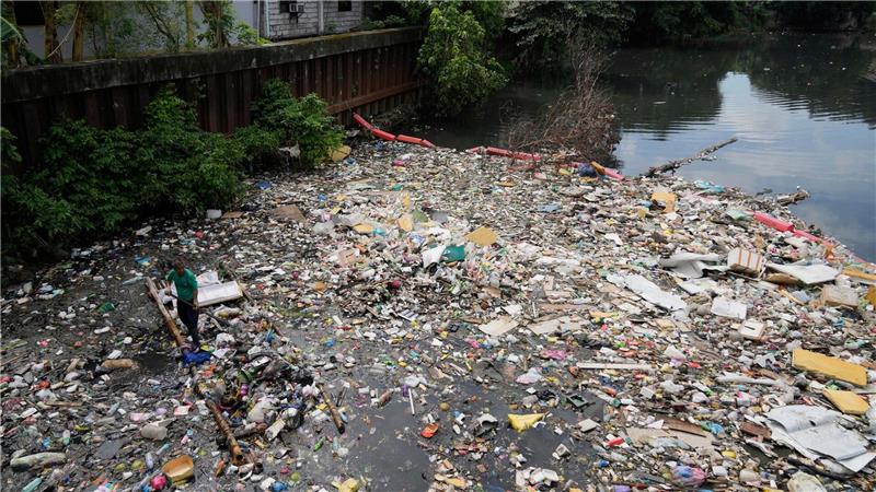 Kampf dem Müll: Ein Arbeiter sammelt Plastikmüll und andere Abfälle am San Juan-Fluss auf den Philippinen ein.