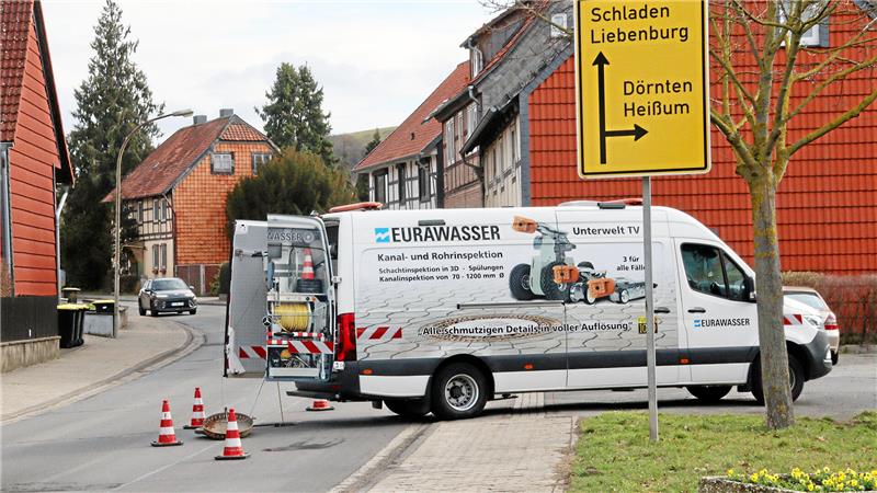 Ein Fahrzeug von Eurawasser steht an einer Straße, Kabel führen in einen geöffneten Kanaldeckel.