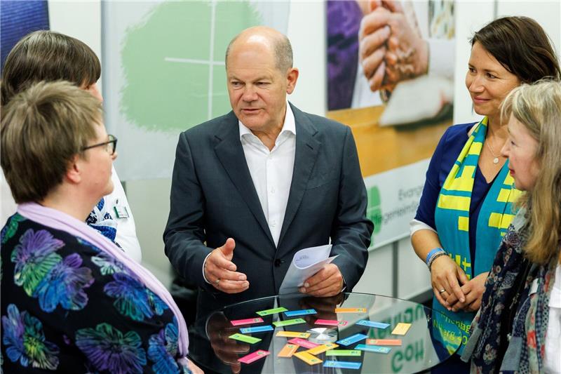 Krieg und Klima: Ein ungewöhnlicher Kirchentag Kanzler Olaf Scholz unterhält sich bei einem Rundgang auf dem Messegelände.