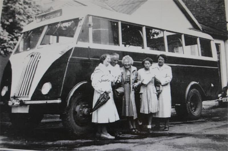 Unternehmensgründer Karl Aßmann steht mit seiner Familie vor einem Reisebus. 