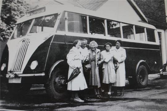 Unternehmensgründer Karl Aßmann steht mit seiner Familie vor einem Reisebus. 