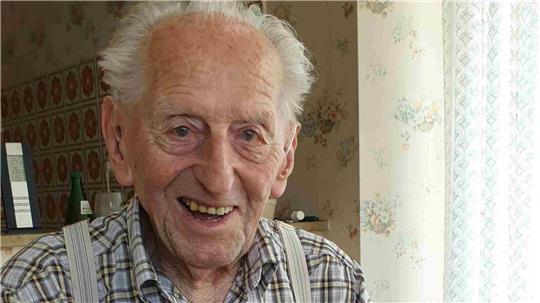 Karl Haidle sitzt an seinem 104. Geburtstag an einem Tisch und liest Zeitung.