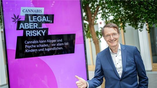 Karl Lauterbach vor einem Plakat einer Aufklärungskampagne zu den Gefahren von Cannabis.