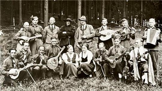 Eine Gruppe Menschen posiert im Wald und mit Instrumenten für ein Foto