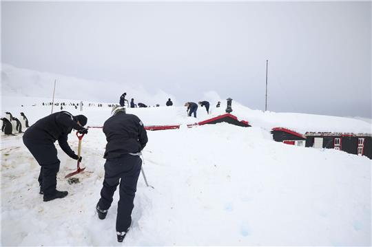 Kaum noch zu sehen, da eingeschlossen von Schnee: Mitglieder der Schiffsbesatzung der HMS Protector und des UKAHT-Teams schaufeln ein  Gebäude in Port Lockroy frei.