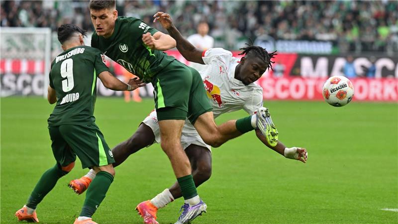 Kaum zu stoppen: Leipzigs Torschütze Johan Bakayoko (r) wird von den Wolfsburgern Joakim Maehle und Mohammed Amoura bedrängt.