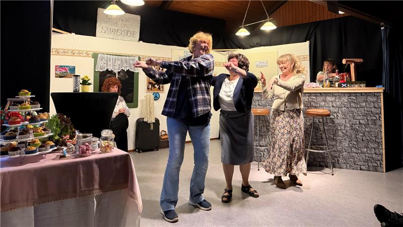 Das Foto zeigt drei Frauen, die einen Tanz vorführen.