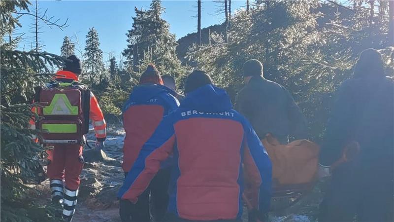 Mehrere Menschen tragen eine verletzte Person einen Weg bergauf.