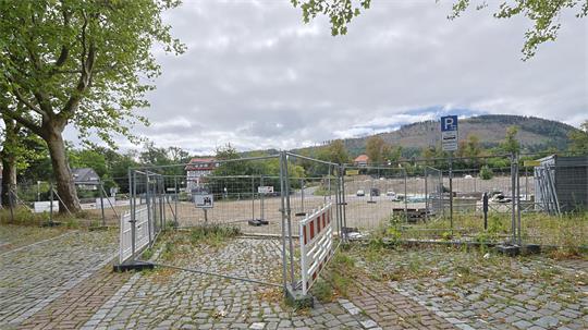 Absperrung mit Bauzaun und Warnbake auf gepflastertem Platz vor bewölktem Himmel und Hügel im Hintergrund