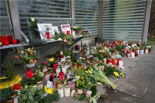 Kerzen und Blumen stehen und liegen im Bahnhof Brokstedt in einem Wartehäuschen.