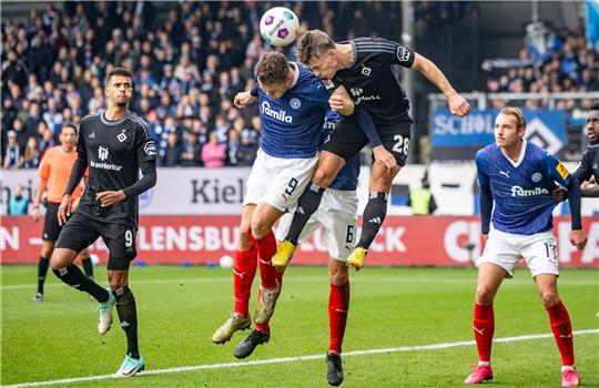 Kiels Benedikt Pichler (M,l), Kiels Marko Ivezic (verdeckt) und Hamburgs Miro Muheim (M,r) kämpfen um den Ball.