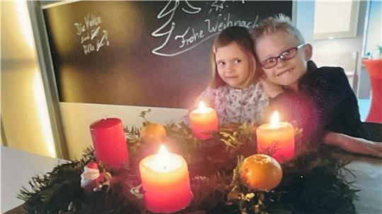 Das Bild zeigt Ida und Emil, die Enkelkinder Autorin, vor einem Adventskranz.