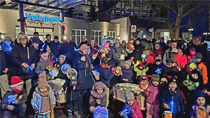 Familien stehen mit ihren Laternen vor der geschmückten Volksbank.