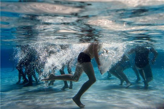 Kinder spielen im Becken eines Freibads.