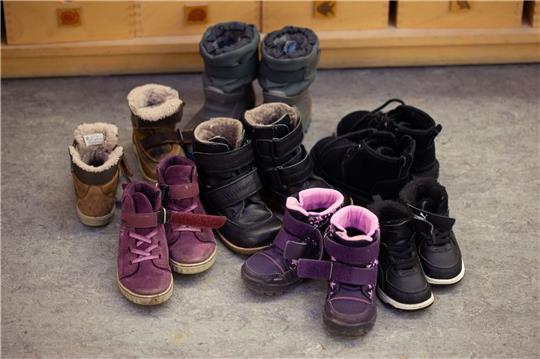 Kinderschuhe und -stiefel sind auf dem Boden in einer Kindertagesstätte abgestellt.