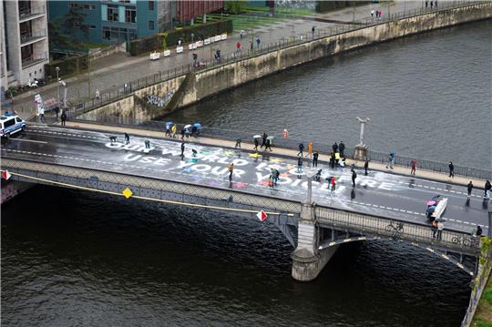 Klimaaktivisten der Bewegung Fridays for Future malen auf der Marschallbrücke in Berlin den Schriftzug «Our world is on fire - use your voice!».