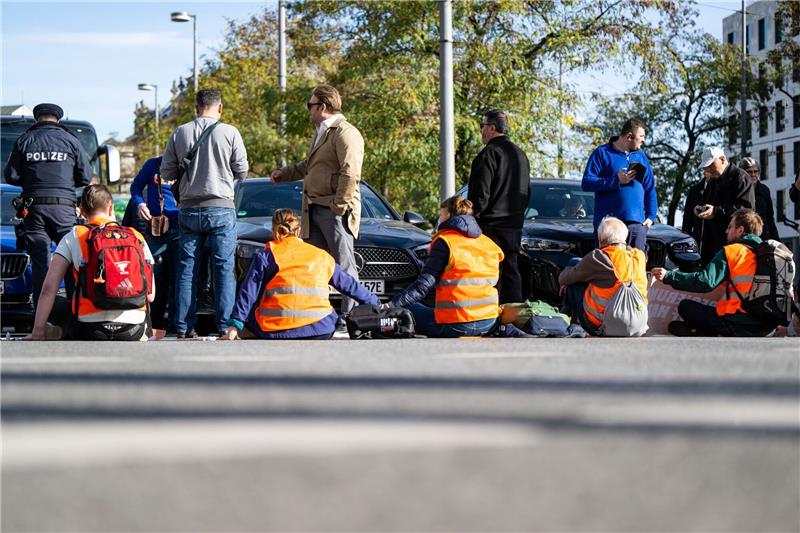 Union fordert härtere Strafen für Klima-Aktivisten Klimaaktivisten haben sich am Karlsplatz in der Münchner Innenstadt auf die Fahrbahn geklebt und blockieren die Straße.