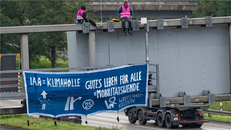 Klimaaktivisten protestieren auf der A9 in der Nähe der Allianz Arena mit einem Plakat gegen die IAA.