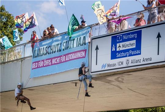 Klimaaktivisten von Extinction Rebellion  seilen sich in München von einer Brücke  ab.
