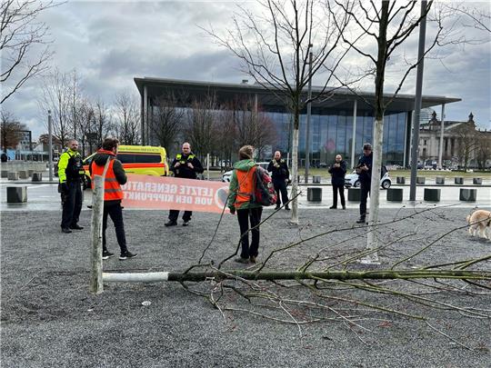 Klimaschutz-Demonstranten stehen an einem gefällten Baum am Bundeskanzleramt.