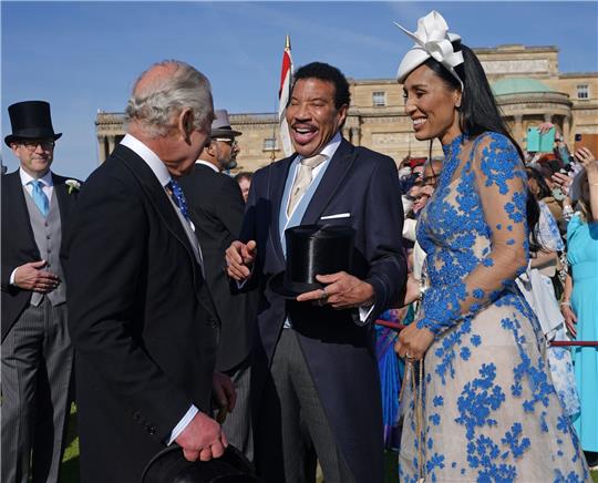 König Charles III. (l) spricht während der Gartenparty im Buckingham Palace mit Lionel Richie (M) und Lisa Parigi.