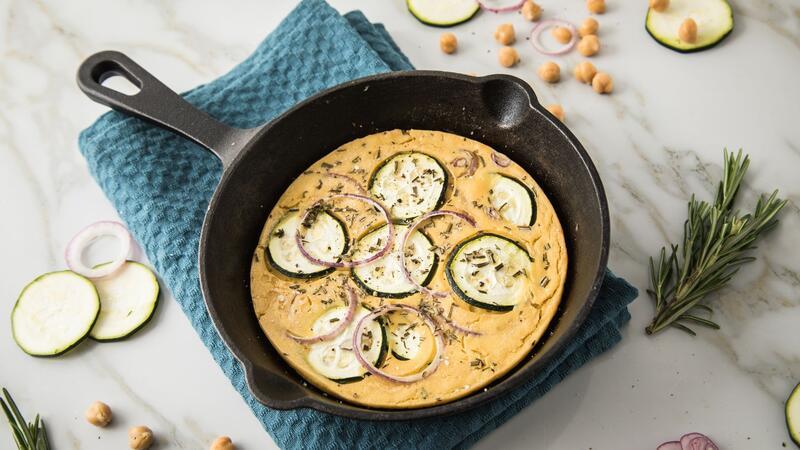 Köstliche Socca Pizza aus Kichererbsenmehl mit Zucchini, Rosmarin und roten Zwiebeln.