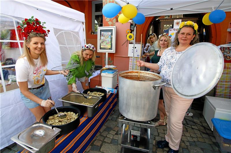 Köstliches aus dem Kochtopf: Yuliia Kovalenko (li.) und ihre Mitstreiterinnen am Ukraine-Stand sind bestens auf hungrige Gäste vorbereitet. Foto: Epping